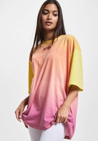 Oversized t-skjorte laget av bomull, med en gul til rosa ombre-gradient; korte ermer med rund hals og brodert tekst.