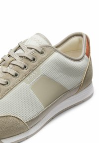 Baskets BOSS beige et blanches avec détails en mesh et daim, design à lacets, col rembourré et semelle en caoutchouc avec grip texturé.