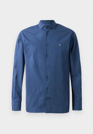 Chemise bleu marine à boutons avec un col pointu, des manches longues et un petit logo brodé sur la poitrine. Fabriquée en tissu lisse.