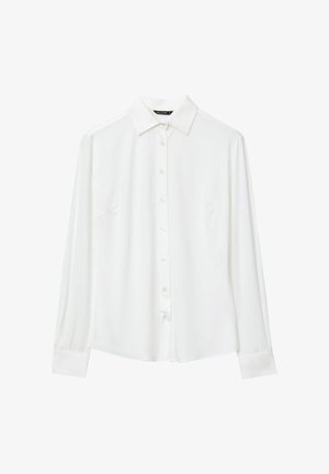 Camicia bianca a maniche lunghe realizzata in tessuto liscio, con colletto a punte, chiusura con bottoni a tutta lunghezza e taschino sul petto.
