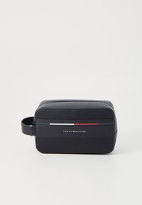 Námorná nylonová toaletná taška s obdĺžnikovým tvarom, ktorý má textúrovaný povrch, kožené akcenty a červené, biele a modré pruhy na prednej strane.