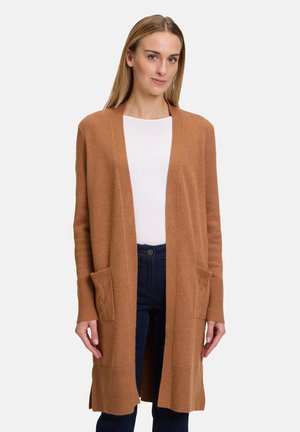 Cardigan long couleur camel en matière douce, doté de poches latérales avec un motif de tricot en cable et des poignets côtelés. Design à devant ouvert.