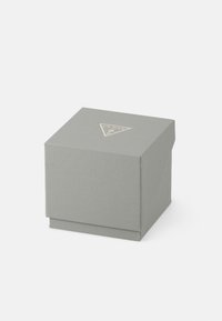 Graue strukturierte quadratische Box mit einem Deckel, auf dem sich ein metallisches dreieckiges Logo befindet. Glatte Oberfläche, kompaktes Design, minimalistische Ästhetik.
