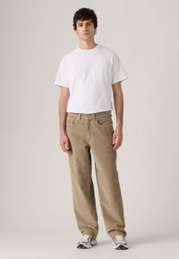 Lightweight white t-shirt and beige corduroy pants with a straight fit. The pants feature front pockets and a textured finish.