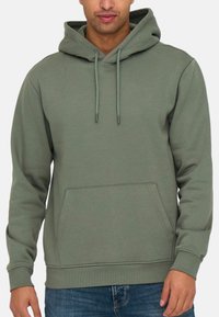 Oliwkowy hoodie wykonany z miękkiego materiału, z przednią kieszenią, regulowanym kapturem na sznurki oraz ściągaczami przy mankietach i dolnym brzegu. Prosty design.