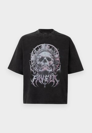 Camiseta negra de gran tamaño con un gran gráfico de calavera desgastada que lleva una corona con pinchos y está rodeada de formas abstractas espinosas en gris y púrpura.