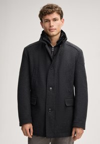 Cappotto in misto lana grigio scuro con colletto strutturato, chiusura a bottoni e due tasche frontali. Texture liscia con un sottile motivo a spina di pesce.