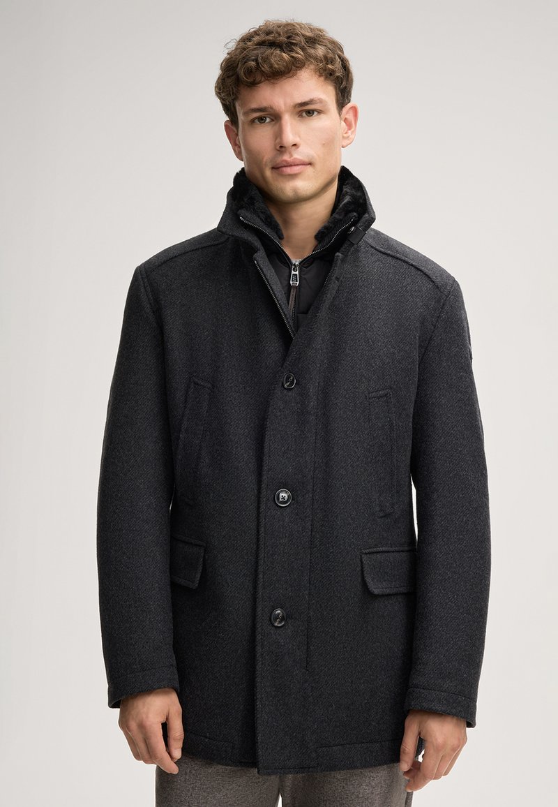 Cappotto in misto lana grigio scuro con colletto strutturato, chiusura a bottoni e due tasche frontali. Texture liscia con un sottile motivo a spina di pesce.