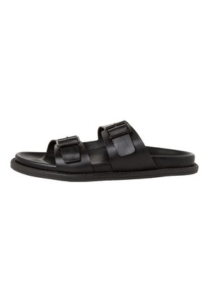 Black leather sandals with two adjustable buckles, open-toe design, flat sole, and smooth texture, featuring minimalistic styling.