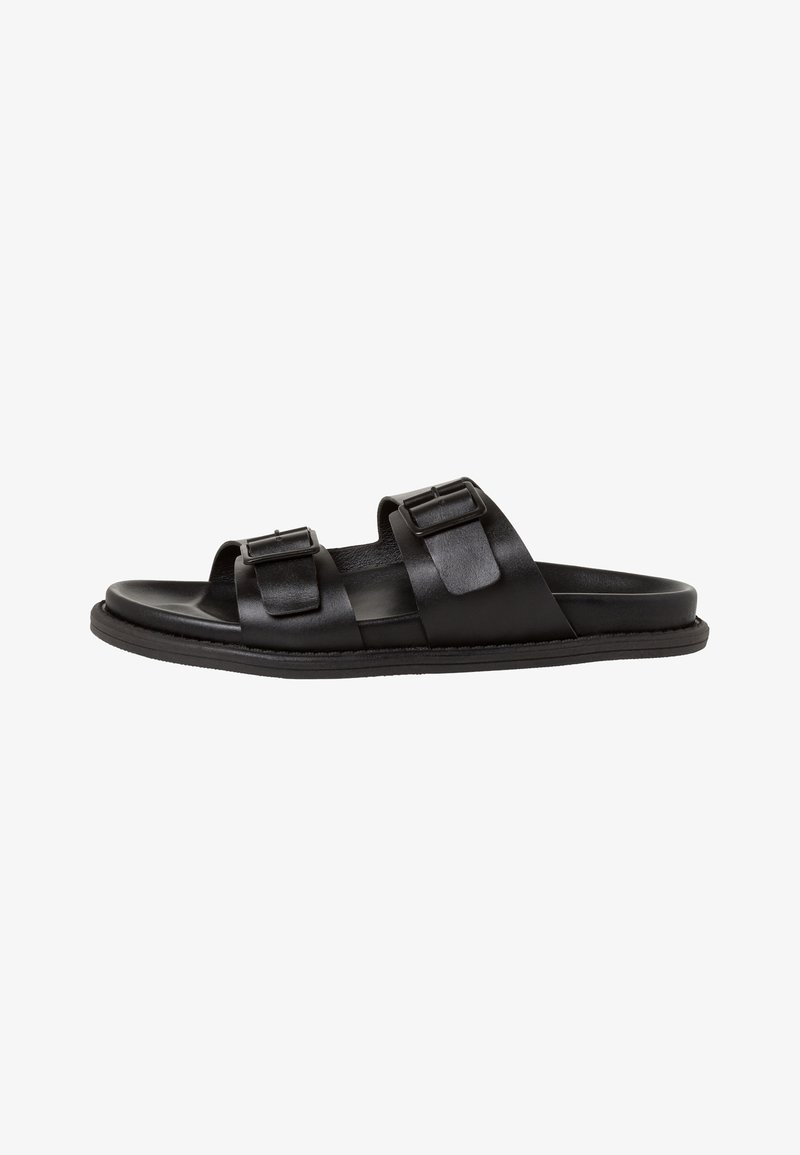 Zwarte leren sandalen met twee verstelbare gespen, open teen ontwerp, platte zool en gladde textuur, gekenmerkt door minimalistische stijl.