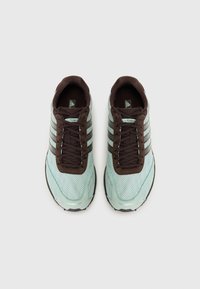Sportskor med mintgrön meshovandel, bruna mockadetaljer och tre mörka ränder. Har snörning framtill och en texturerad gummisula.