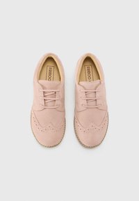 Svijetlo ružičaste suede cipele s brogue dizajnom, koje imaju valoviti rub, suptilne perforacije i bež vezice, postavljene na sintetičku potplatu.