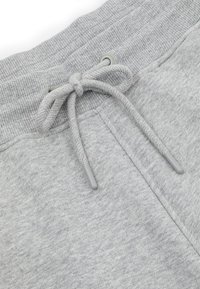 Szare spodnie dresowe ze ściągaczem w pasie, wykonane z fakturowanej tkaniny z metalowymi oczkami na sznurek. Miękki materiał o gładkim wykończeniu.