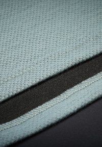 Textilní vrstvy světle modré síťoviny a černé látky, s viditelným švem. Horní vrstva má strukturovaný vzor, zatímco černá látka je hladká.