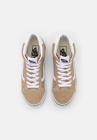 Baskets montantes en daim fauve avec des lacets blancs et des bandes latérales. Elles présentent un col rembourré et un logo Vans noir sur la languette.