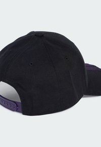 Gorra negra de tela con una visera plana. Presenta un cierre ajustable de snapback morado y orificios de ventilación en la parte superior.