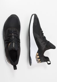 Sorte atletiske sneakers med mesh-overdel, hvid sål og guld detaljer på siden. Har flade snørebånd og polstret krave.