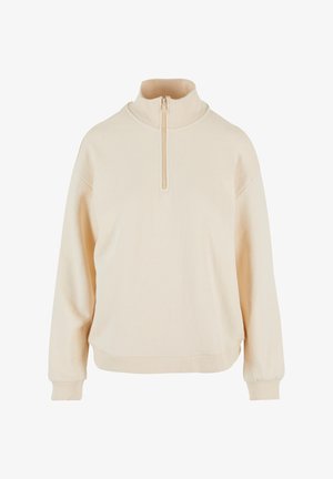 Beige pullover-sweater, millelõhikuga kaelus, neljandiku tõmblukuga ees, lose sobivus ja soonilised varrukad. Pehme tekstuur puhta disainiga.