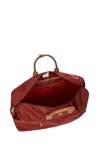 Sac de voyage en nylon rouge avec des poignées en cuir, fermeture éclair et une poche intérieure. Texture lisse et design intérieur spacieux.