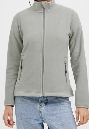 Hellgraue Fleecejacke mit Frontreißverschluss und Reißverschlusstaschen an den Seiten, getragen mit hellblauen Jeans.