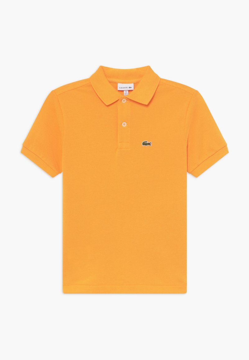 Pomarańczowa koszulka polo wykonana z bawełny; ma klasyczny kołnierzyk, zapięcie na trzy guziki oraz zielone logo krokodyla po lewej stronie klatki piersiowej.