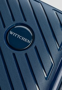 Navy blue textured surface suitcase with diagonal grooves and a circular logo in the center reading "WITTCHEN." Durable material finish.