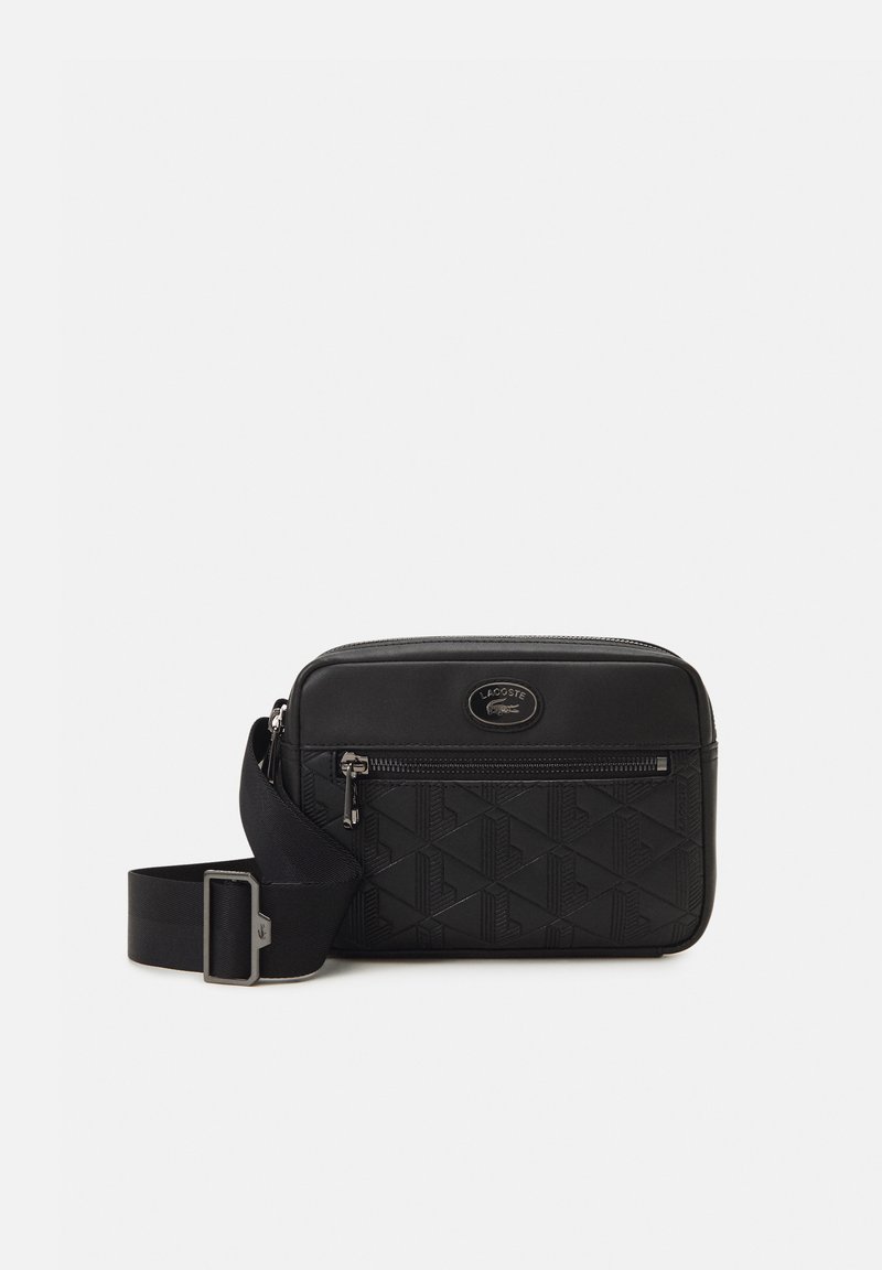 Geantă crossbody neagră cu un finisaj neted și texturat. Dispune de o carghină frontală cu fermoar, curea ajustabilă și un design geometric embosat.