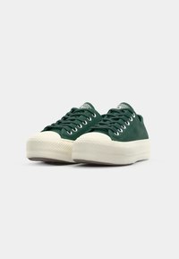 Grønne sued sneakers med lavt design, hvit gummisåle, rund tå og flate lisser. Har metallhull og logo på tungen.
