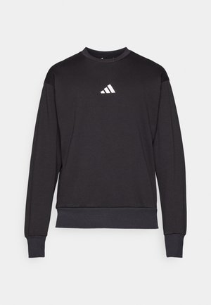 Μαύρη φούτερ μπλούζα με μακριά μανίκια, στρογγυλή λαιμόκοψη και ριμπ ελαστικά μανίκια. Διαθέτει ένα μικρό λευκό λογότυπο της Adidas στο στήθος. Μαλακή υφή υφάσματος.