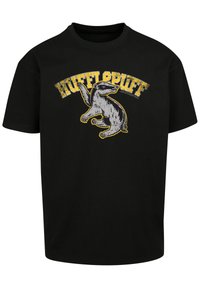 Svart bomull T-skjorte med et grafisk design av en dverg, med gul tekst som leser "HUFFLEPUFF" over, i en slitt stil.