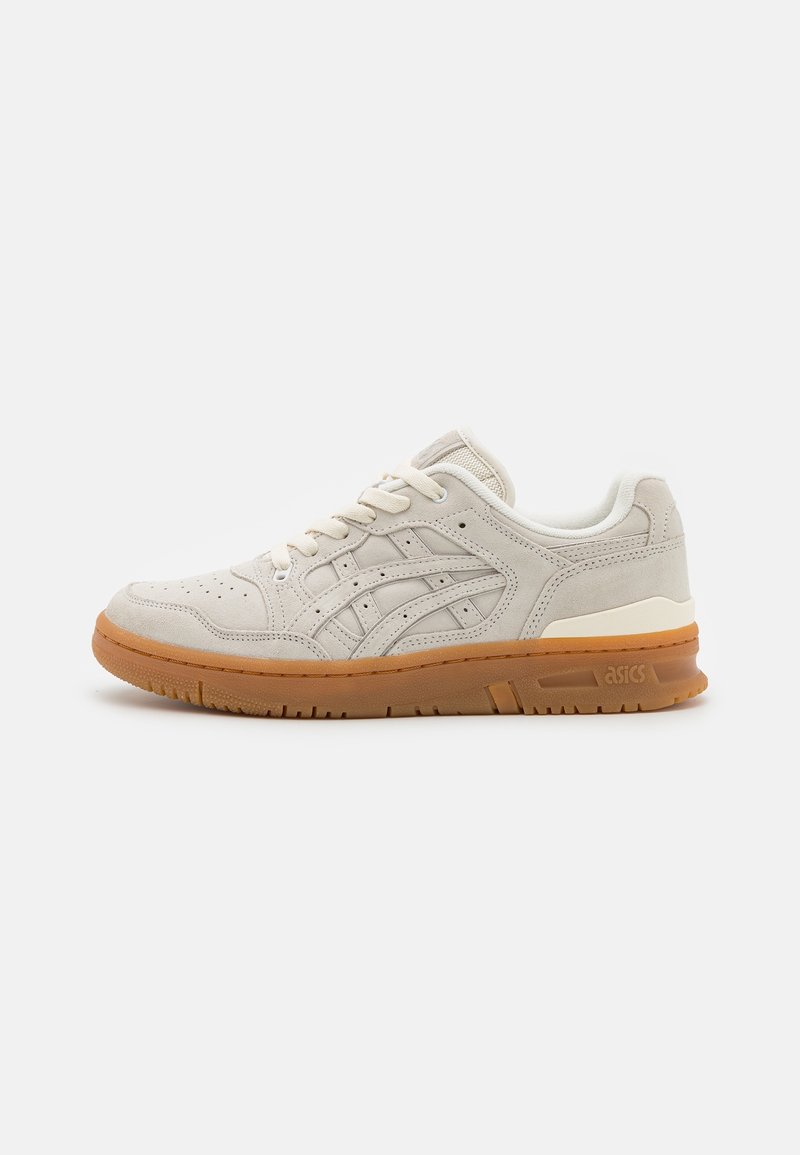 Baskets en daim beige clair avec fermeture à lacets et semelle en gomme, dotées de bandes latérales cousues et de perforations sur la zone des orteils.