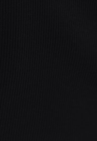 Svart ribbad tyg, närbild, med vertikala linjer och en slät yta, som visar dess stretchbarhet och struktur.