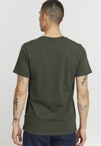 Mørke olivengrøn t-shirt med korte ærmer og rund halsudskæring. Blød, glat tekstur; enkel design uden synlige mønstre eller accenter.