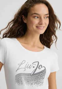 T-shirt en coton blanc avec un design graphique en strass argentés portant l'inscription "Liu Jo", doté d'un col rond et de manches courtes.