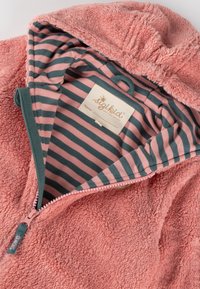 Felpa rosa soffice con zip, caratterizzata da un interno a strisce nei colori rosa e teal, e un'etichetta cucita. Texture morbida e design accogliente.