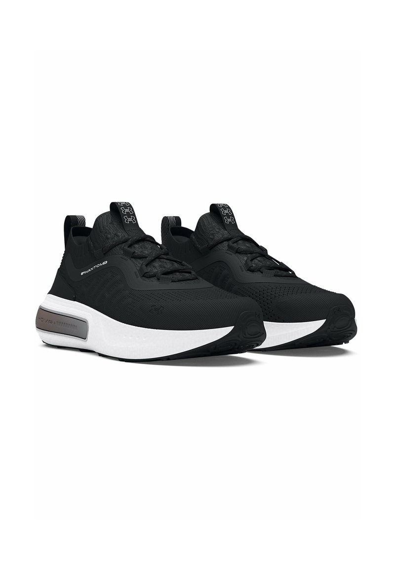Baskets de sport noires avec une tige texturée, fermeture à lacets et semelle intermédiaire blanche. Elles présentent un onglet au talon noir et des accents sur la languette.
