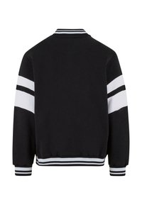 Black sweatshirt with white stripes across sleeves, ribbed collar and cuffs. Soft texture, relaxed fit, and elastic waistband detail.