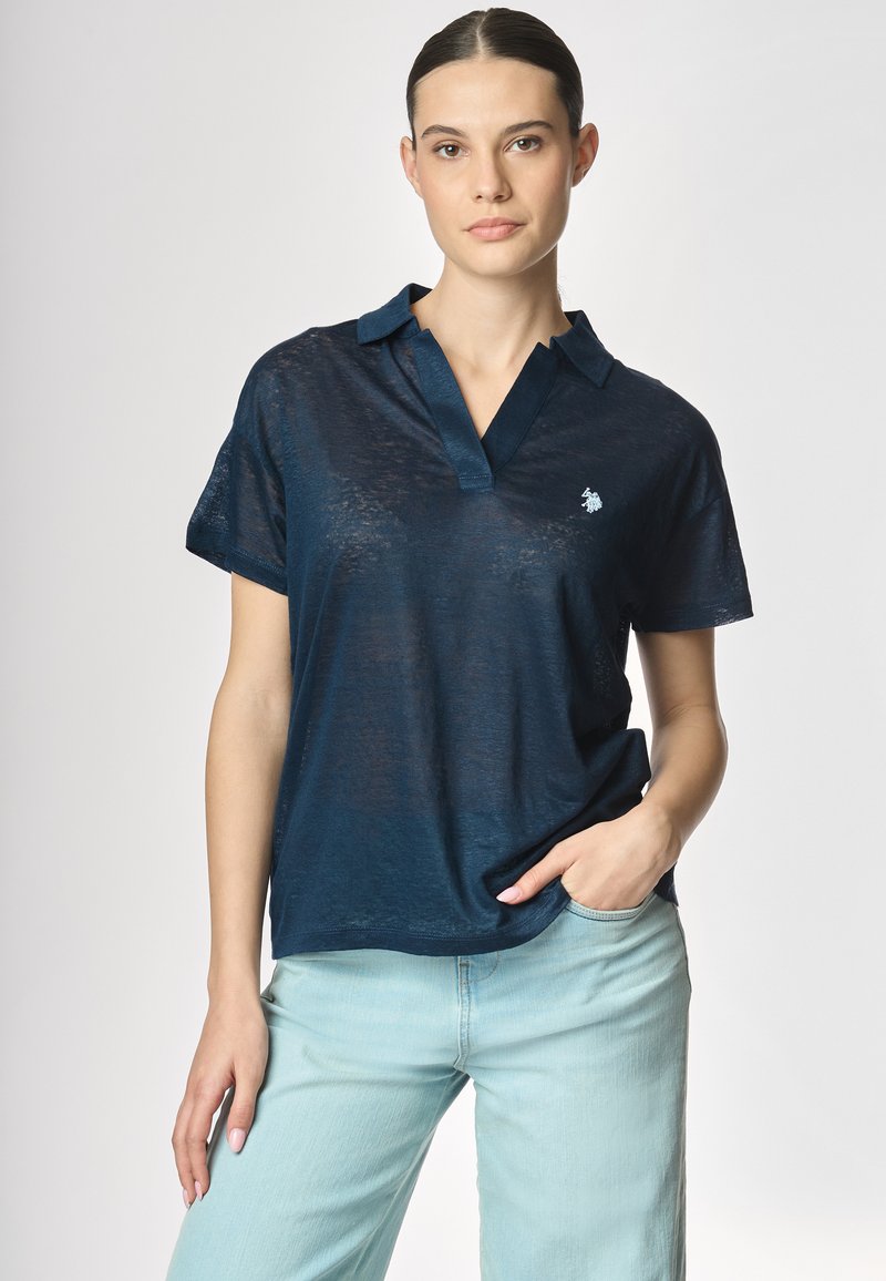 Polo shirt blu navy in un tessuto leggero e testurizzato, con colletto a punte e un piccolo logo ricamato sul lato sinistro del petto.