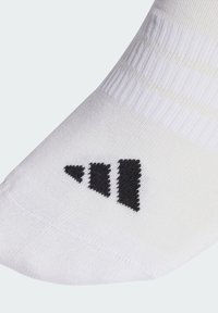 Calcetín deportivo blanco con textura acanalada y logo negro que presenta tres franjas paralelas en el lateral. Punta reforzada para mayor durabilidad.