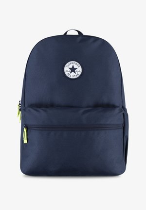 Navy blue fabric backpack with a round white logo, top carry handle, and two zippered compartments featuring neon green pulls.