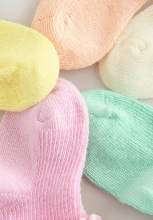 Six bonnets en tricot aux couleurs pastel jaune, pêche, crème, rose et vert menthe, disposés côte à côte.