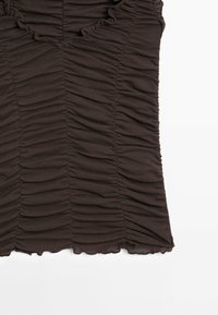 Hnědý top s nařasením a výstřihem do V, vyrobený z texturované látky, s volánkovými okraji a přiléhavým střihem, ležící plochý na bílém pozadí.