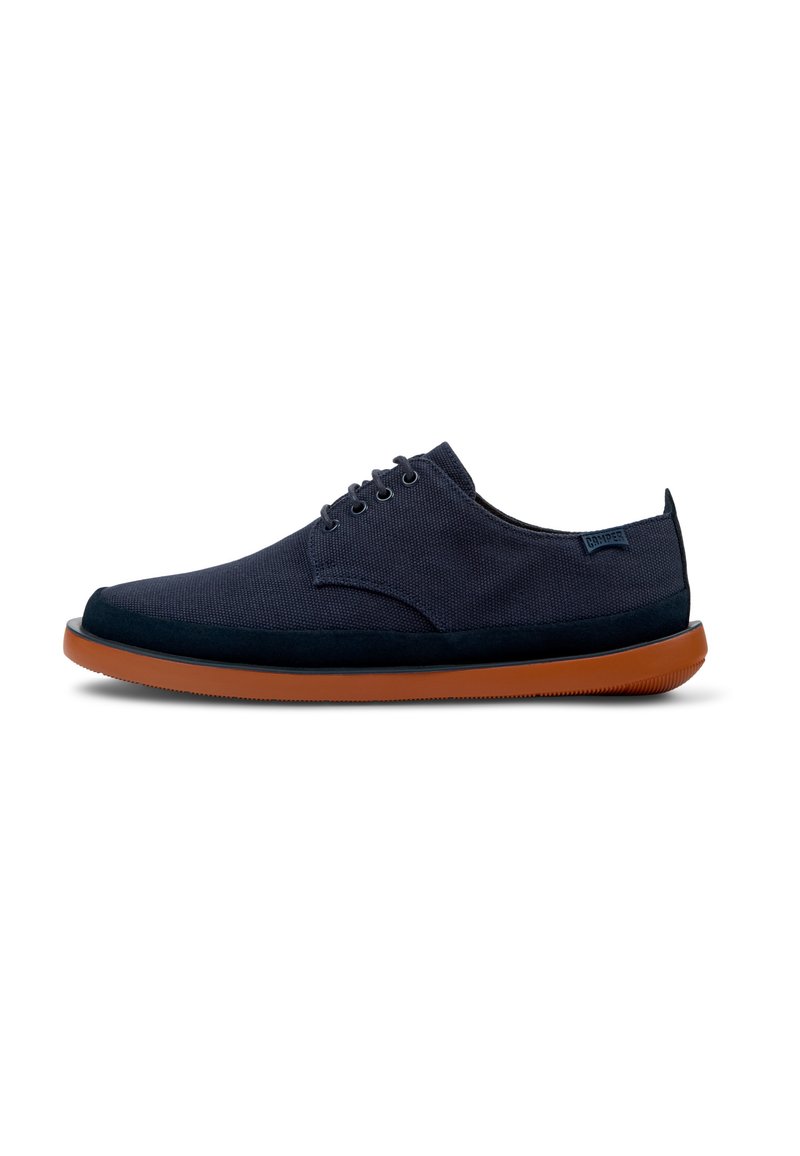 Navy blue canvas shoe with a smooth texture, round toe, six eyelets for laces, and a contrasting brown rubber sole.