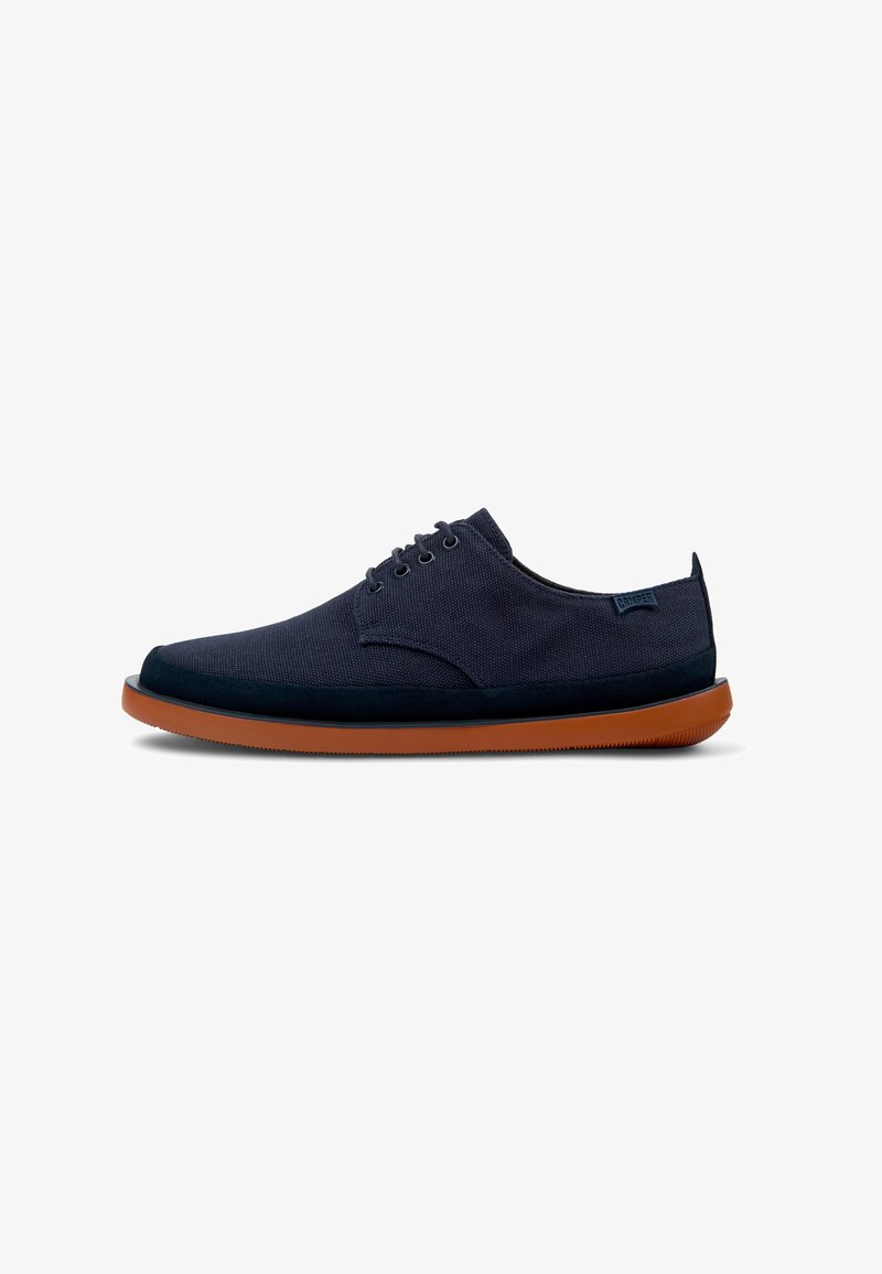 Navy blue canvas shoe with a smooth texture, round toe, six eyelets for laces, and a contrasting brown rubber sole.