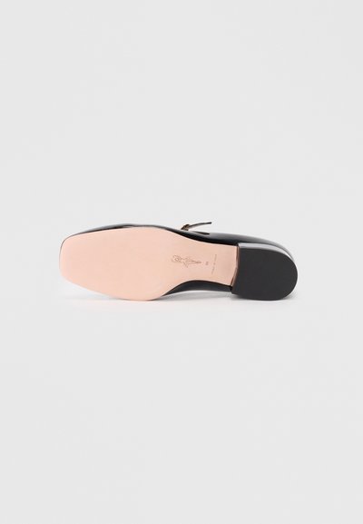 Black patent leather shoe sole with a smooth, pink insole featuring embossed logo details. Slightly rounded toe and low heel design.