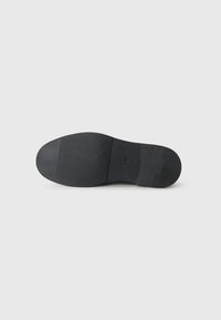 Black shoe sole featuring a smooth finish with textured grip sections and a rounded toe design. Sturdy construction with minimal detailing.