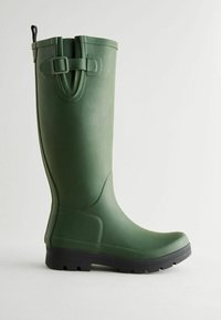 Groene rubberen laars met een gladde textuur, verstelbare strap en een zwarte zool met gripnoppen. Hoge schacht met een ronde neus.