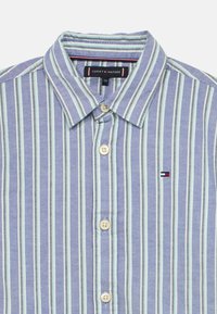 Κοντομάνικο πουκάμισο με κουμπιά σε ανοιχτό μπλε, με στενές λευκές και πράσινες ρίγες, κολάρο και μικρό λογότυπο στο στήθος.