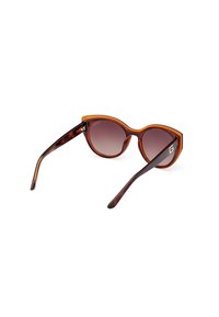 Gafas de sol de carey con forma de gato oversized, lentes degradados y brazos en marrón oscuro contrastante que presentan un acento de logo.