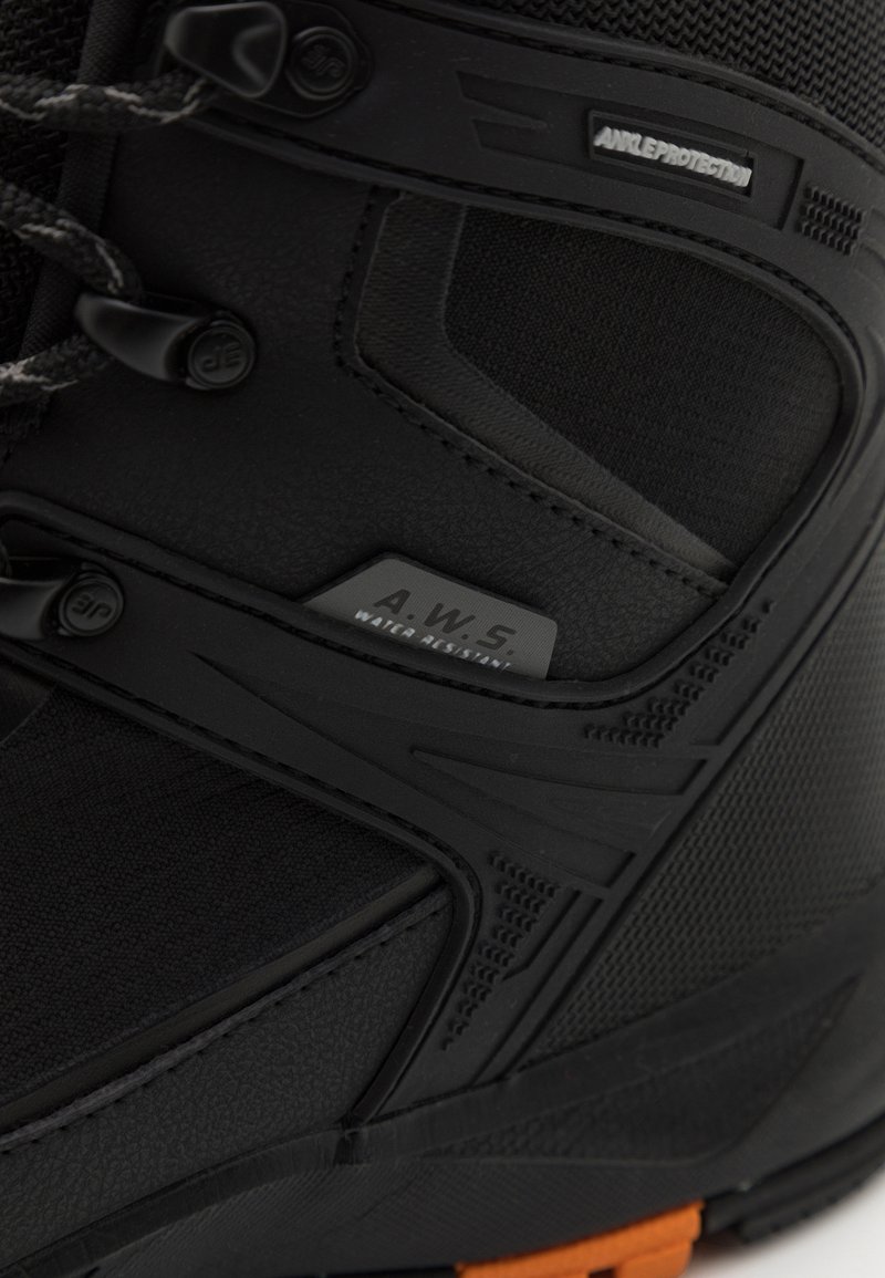 Bota negra impermeable con parte superior sintética texturizada, soporte de tobillo reforzado y suela de goma naranja. Incluye detalle de marca A.W.S.
